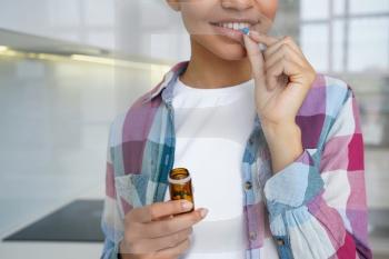 Close-up: Young girl enhances her skin and hair health with dietary supplements, taking vitamins pills for a radiant appearance.