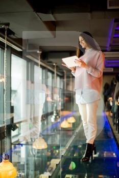 Woman standing on the glass floor with tablet in the hand