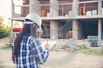 Woman construction engineer writing note wear plaid shirt safety white hard hat at construction site industry labor worker. Architecture Female design drawing engineer civil constrcution real estate