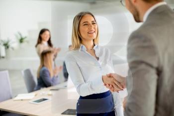 Pretty young business woman handshaking with his colleague in the office