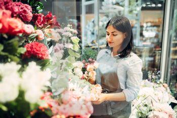 Female florist selects flowers for making a bouquet in floral shop. Floristry service, floristic business. Female florist selects flowers for making bouquet