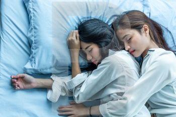 Top view of two Asian women sleeping on bed together. Lesbian lovers and couple concept. People and lifestyles theme.