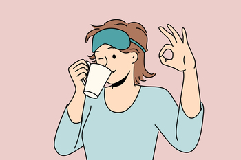 Woman drinks morning coffee after waking up and shows ok gesture standing in sleep mask and pajamas. Girl winks enjoying hot coffee or tea drink to cheer up and get ready for work day. Woman drinks morning coffee after waking up and shows ok gesture standing in sleep mask