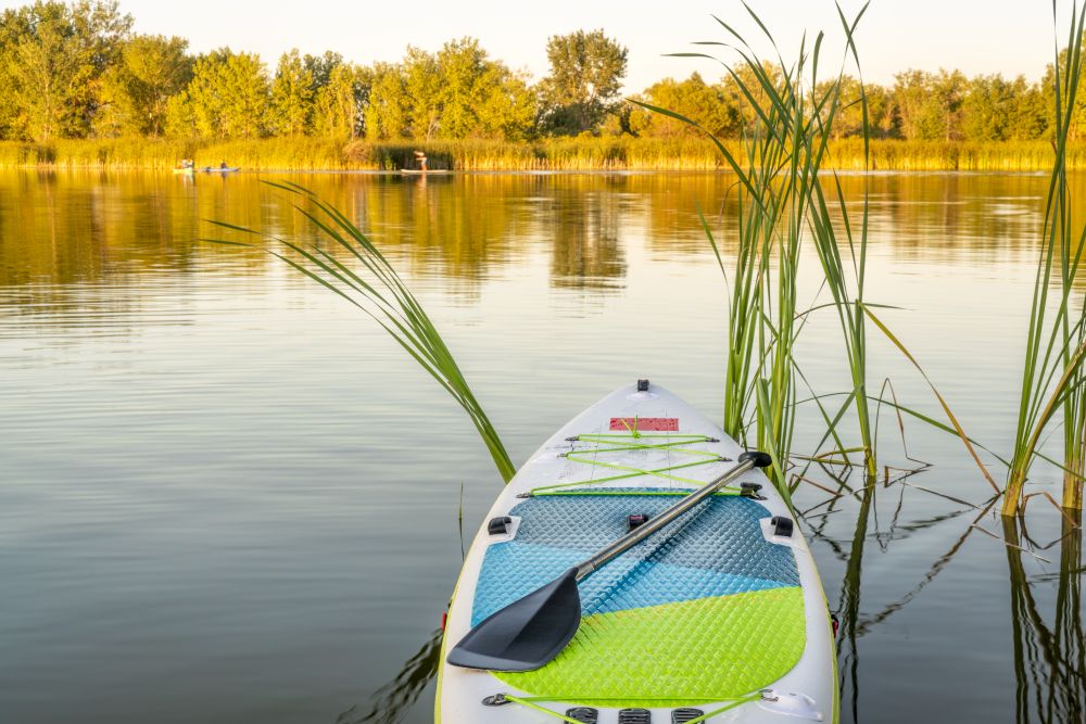 Inflatable stand up paddleboard on calm lake - one of natural areas in Fort Collins, Colorado in late summer scenery