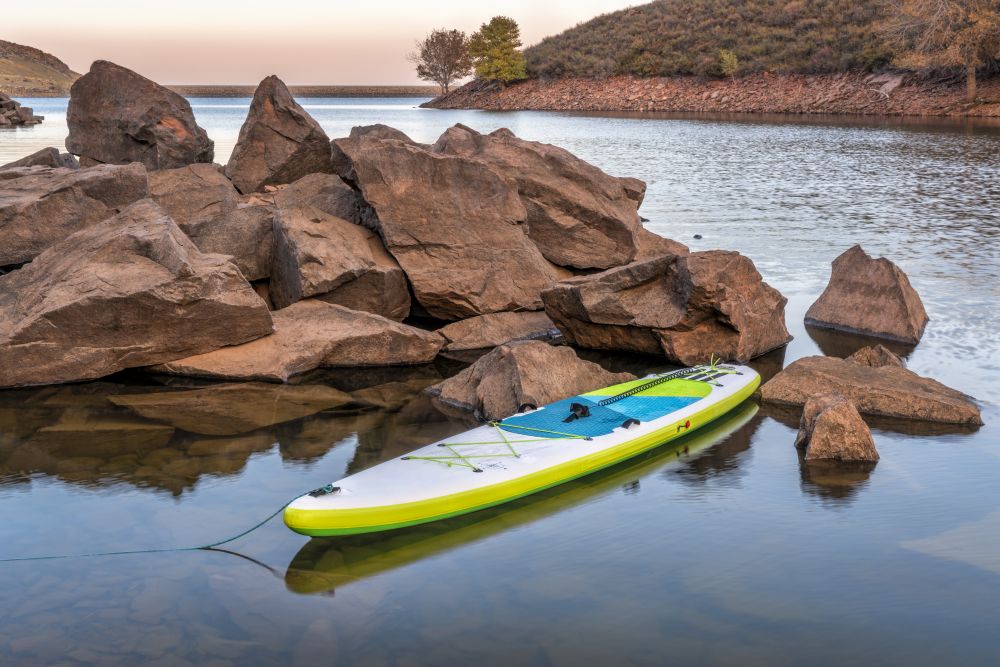 inflatable stand up paddleboard on a rocky shore of mountain lake - Horsetooth Reservoir in northern Colorado in fall scenery