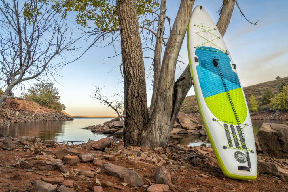 inflatable stand up paddleboard on a rocky shore of mountain lake - Horsetooth Reservoir in northern Colorado in fall scenery