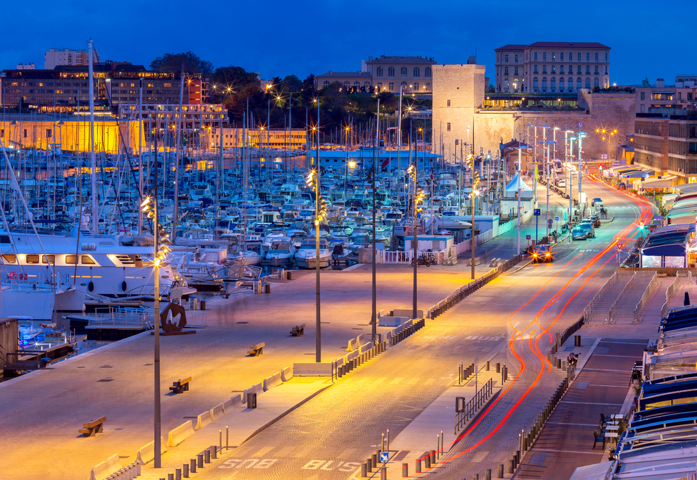 Old port and city embankment in night lighting. Marseilles. France.. Marseilles. View of the old port and the city embankment at sunset.