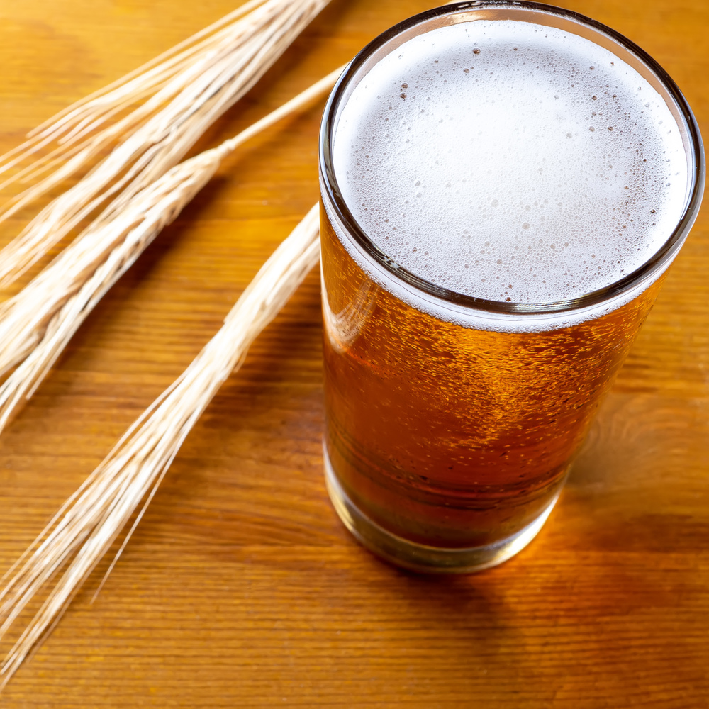 mug of beer with wheat ears on wooden table. Mug of beer on wooden boards with ears of wheat on the background.