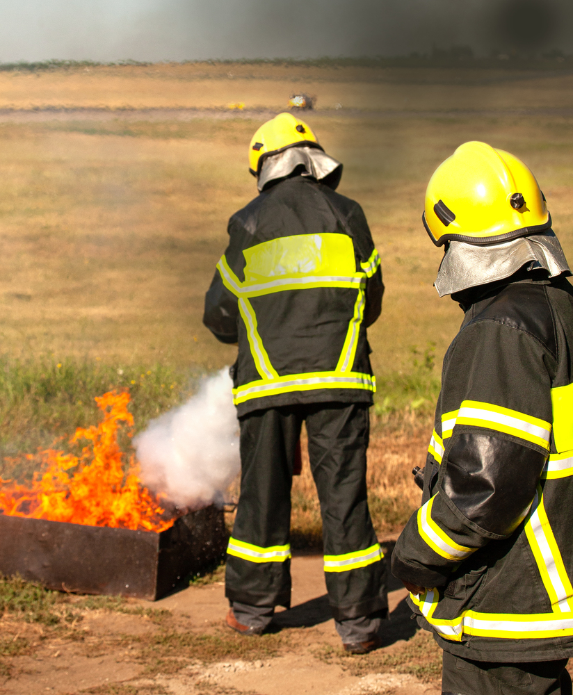 Instructor showing how to use a fire extinguisher on a training fire