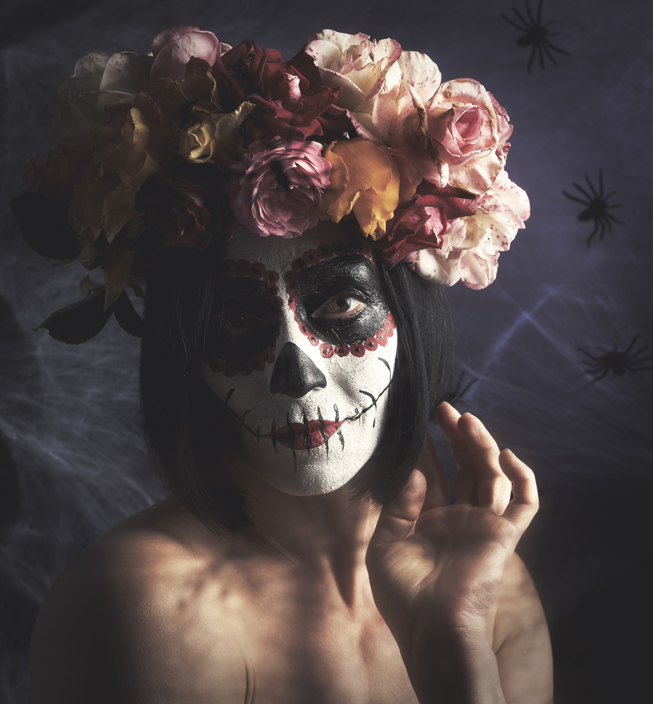 beautiful girl with traditional mexican death mask. Calavera Catrina. Sugar skull makeup. girl dressed in a wreath of roses on a background of white web