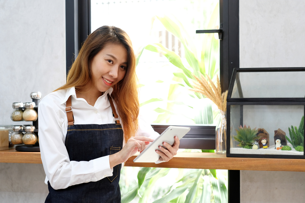 Young asian woman, barista, using tablet at cafe counter background, food and drink concept