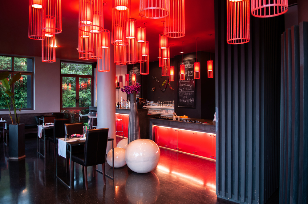 MAY 22,2014 Koh Lanta, Krabi, Thailand - Modern vibrant interior bar lounge with black and white tone furnitures, sexy red pedant lamps, red ceiling and black shiny floor.