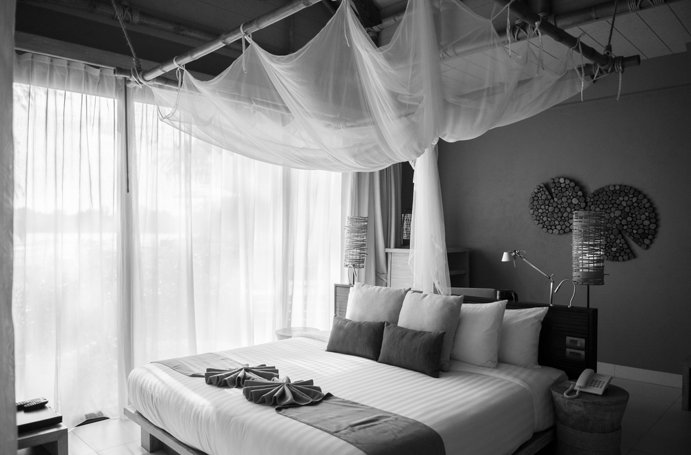 MAY 21, 2014 Krabi, THAILAND - Asian Thai tropical luxury resort room with wooden bed and white curtain. High ceiling hotel room interior. Black and white