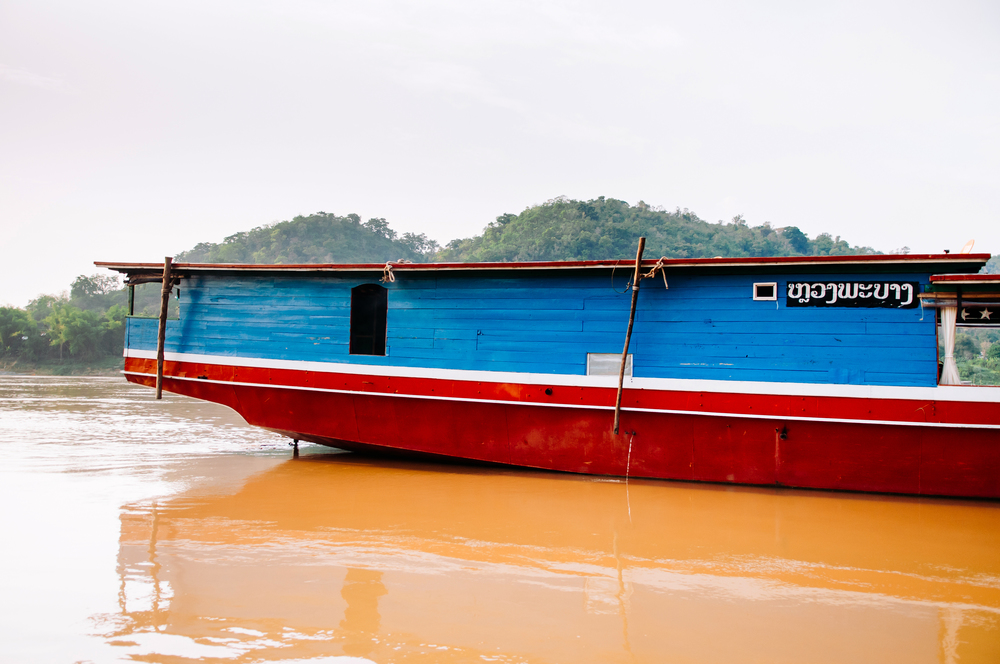 APR 3,2018 Luang Prabang, Laos - Vintage colourful wooden boats in yellow Mekong river during summer with soft evening light