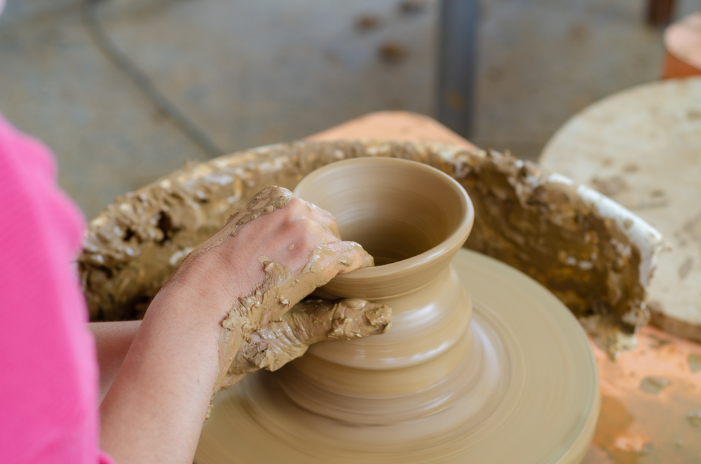 Ceramic working process with clay potter&rsquo;s wheel, close up. The woman is making pottery in studio.