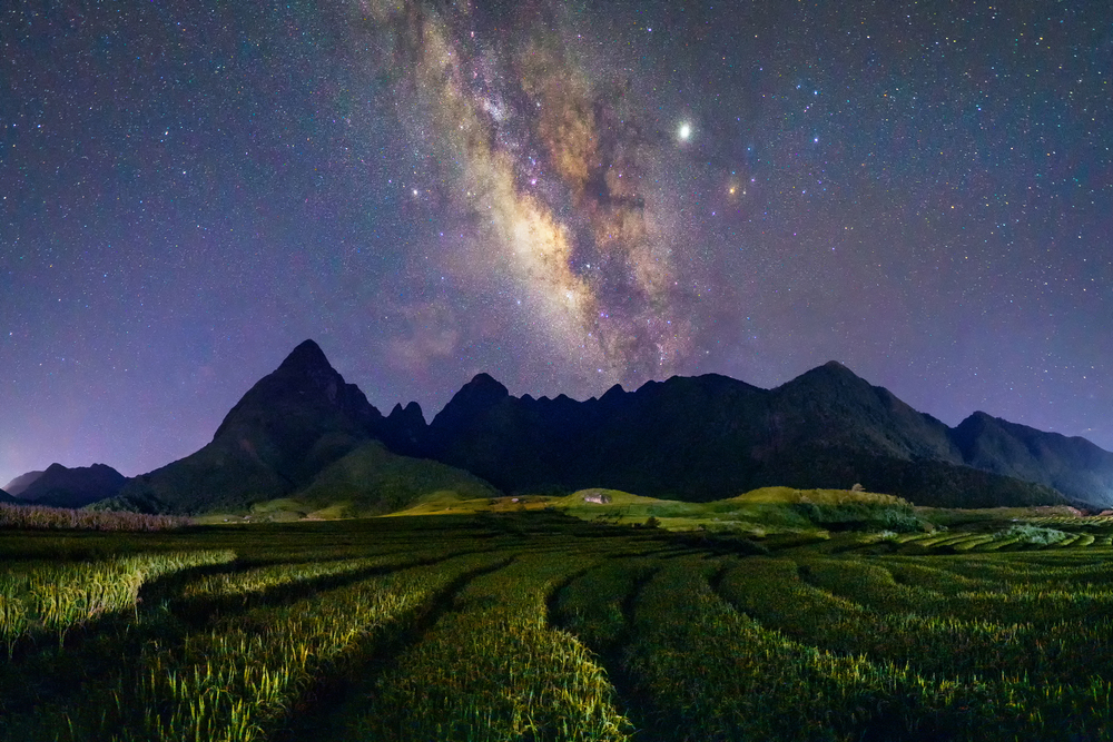 Fansipan mountain hills valley on summer with milky way and paddy rice, agricultural fields at night, Sapa, Vietnam. Nature landscape background.