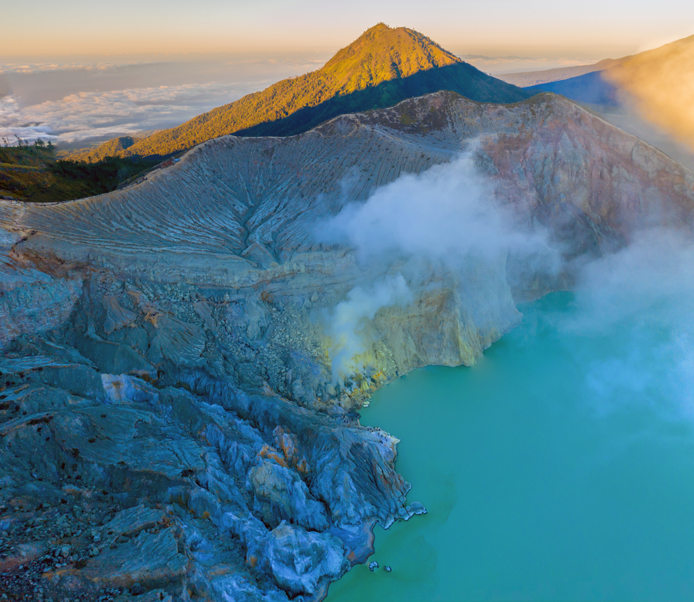 Aerial view of rock cliff at Kawah Ijen volcano with turquoise sulfur water lake at sunrise. Panoramic view at East Java, Indonesia. Natural landscape background.