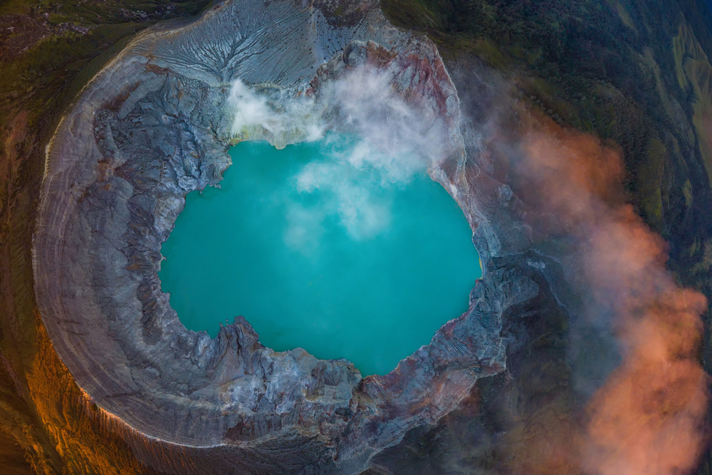 Aerial view of rock cliff at Kawah Ijen volcano with turquoise sulfur water lake at sunrise. Panoramic view at East Java, Indonesia. Natural landscape background.