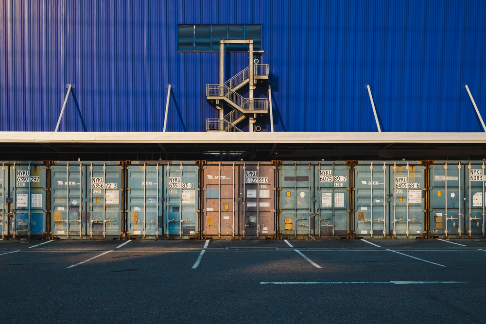 View of many shipping containers doors with fire escape background.