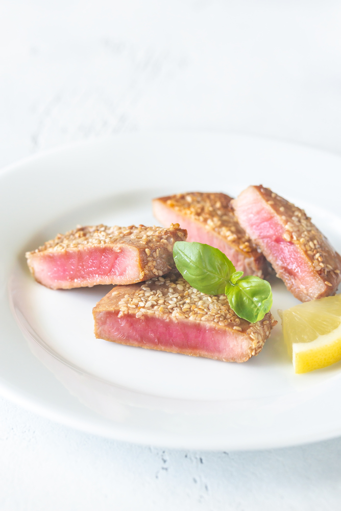 Fried tuna in sesame seeds garnished with fresh basil and slice of lemon