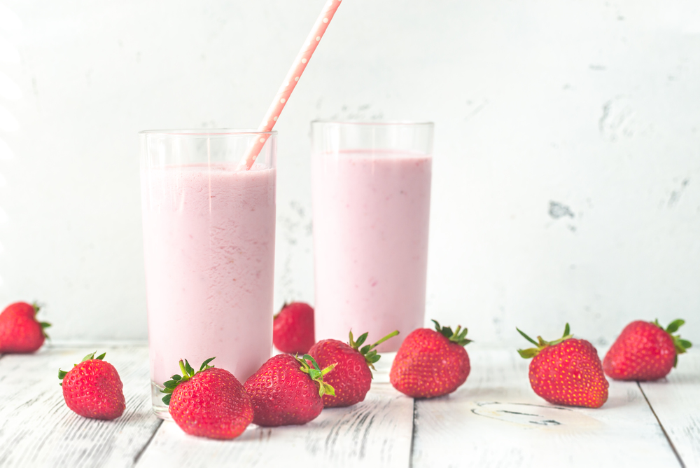 Two glasses of strawberry shake with fresh strawberries