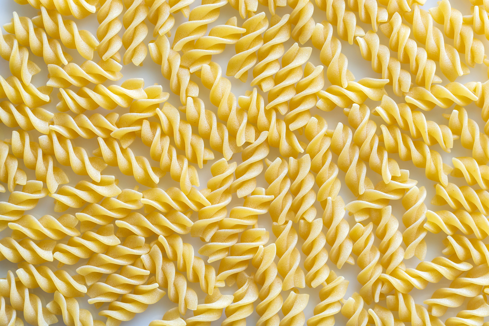 Raw fusilli pasta on the white background: top view