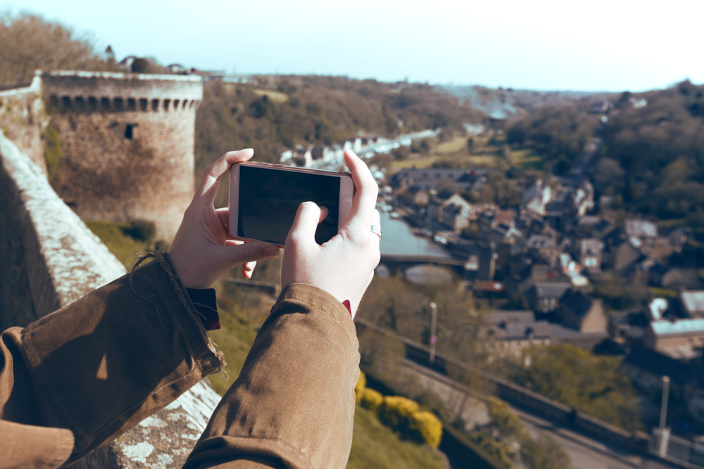 Around the World. girl tourist taking a photo on a smartphone famous city of Dinan. Normandy, France