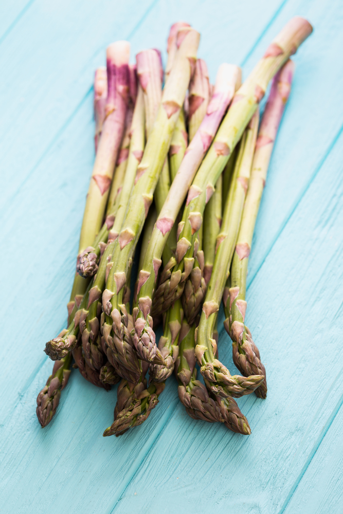 the fresh asparagus on the blue wooden background. veganism and raw foods