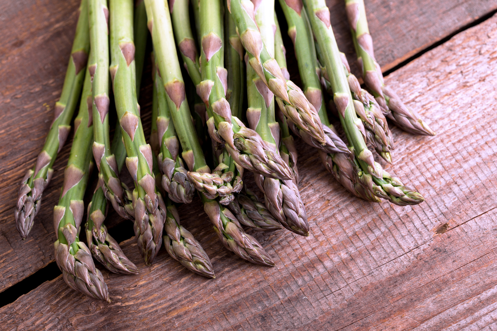 the fresh asparagus on the wooden background. veganism and raw foods