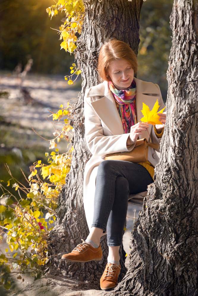 girl in the park holding yellow maple leaves