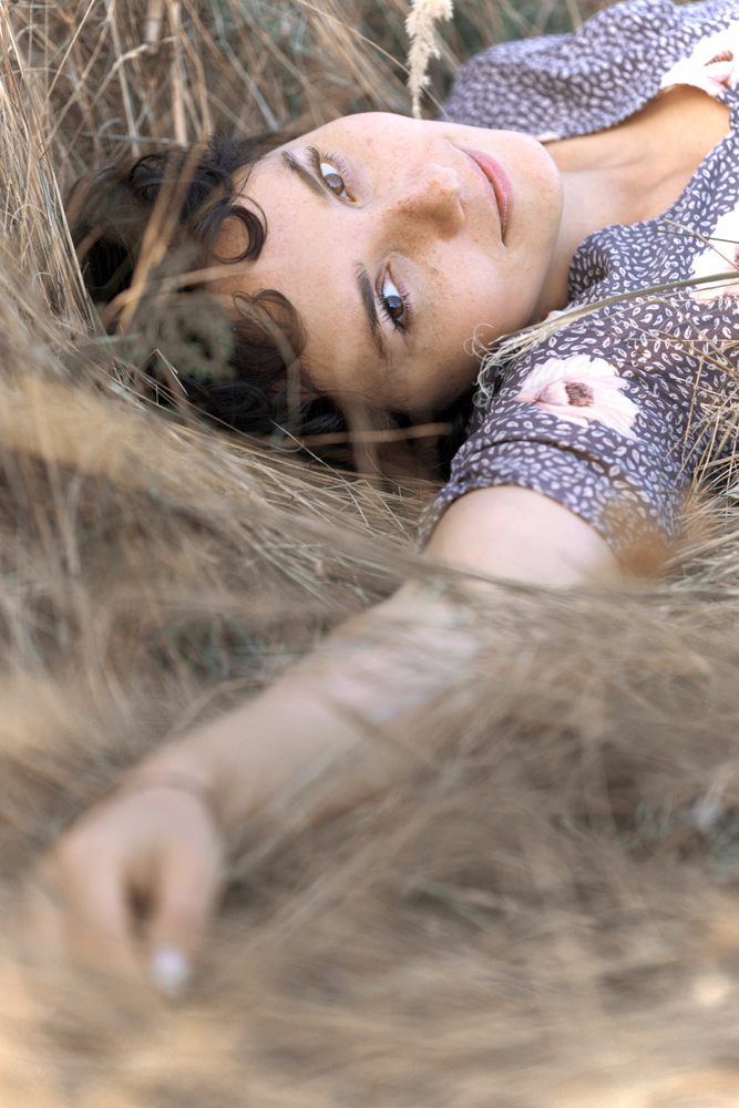 happy smiling girl lies in dry grass and looking at the camera. retro style.