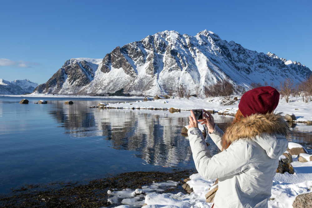 girl travels around lofoten islands and takes pictures on camera. beautiful Norwegian landscape. Norway