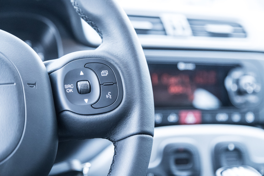 Close up of a steering wheel with remote control, blurry dashboard