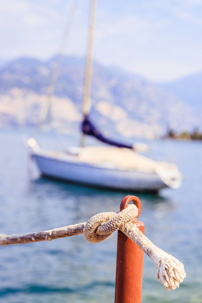 Sailing rope on a wooden dock pier in the foreground, sailing boats in the blurry background