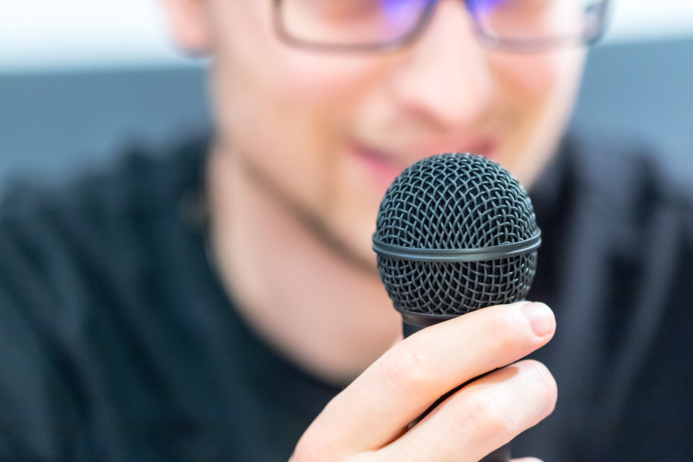 Microphone in the foreground, man taking into it in the blurry background