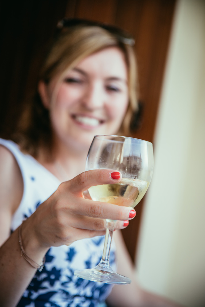 Beautiful young girl with blond hair holds a glass of wine and smiles, holidays