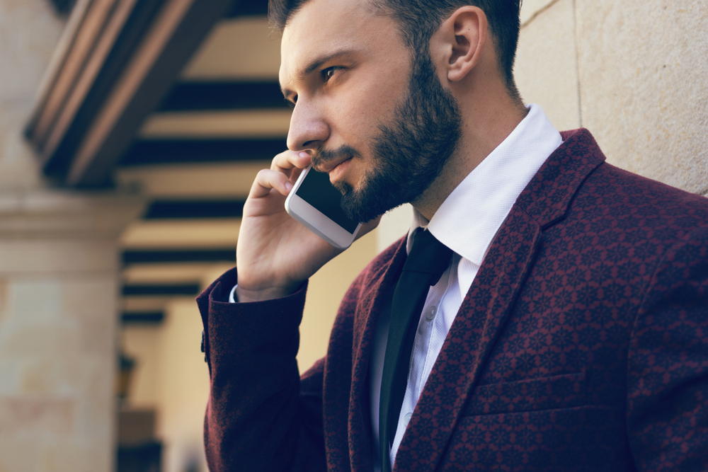 Handsome and fashionable man with a beard talking on the phone in close-up