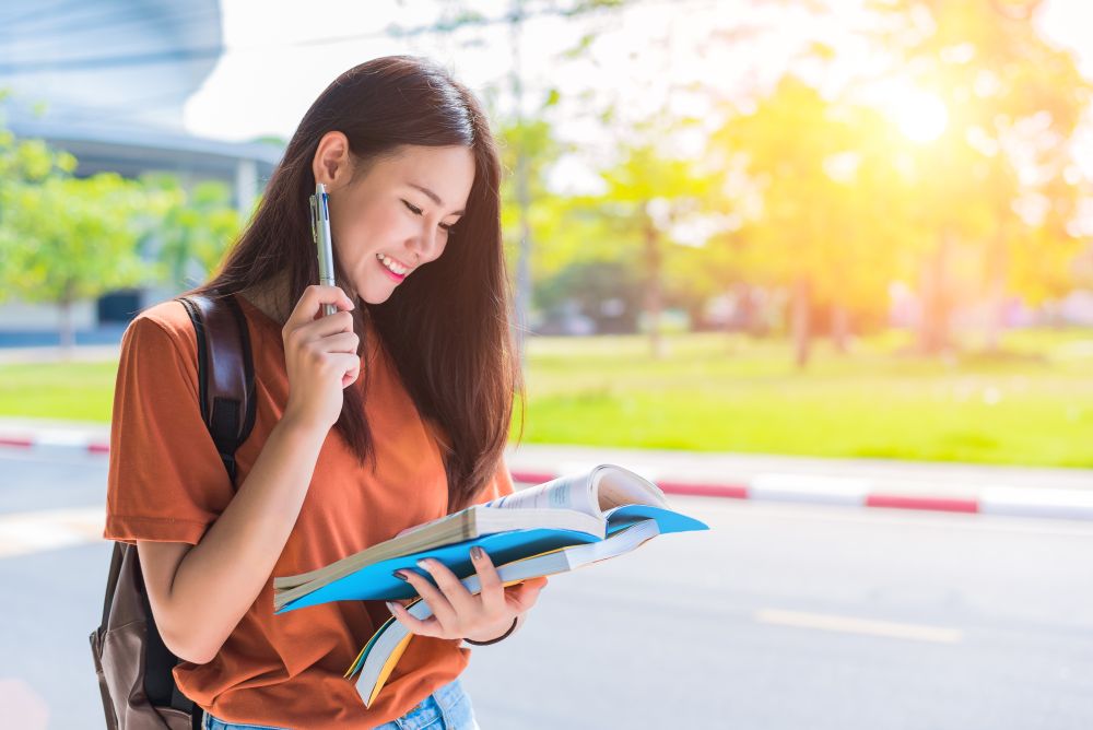 Asian young college woman doing homework and reading books for final examination in campus. University and student concept. Lifestyle and beauty concept. Teenager and Learning theme.