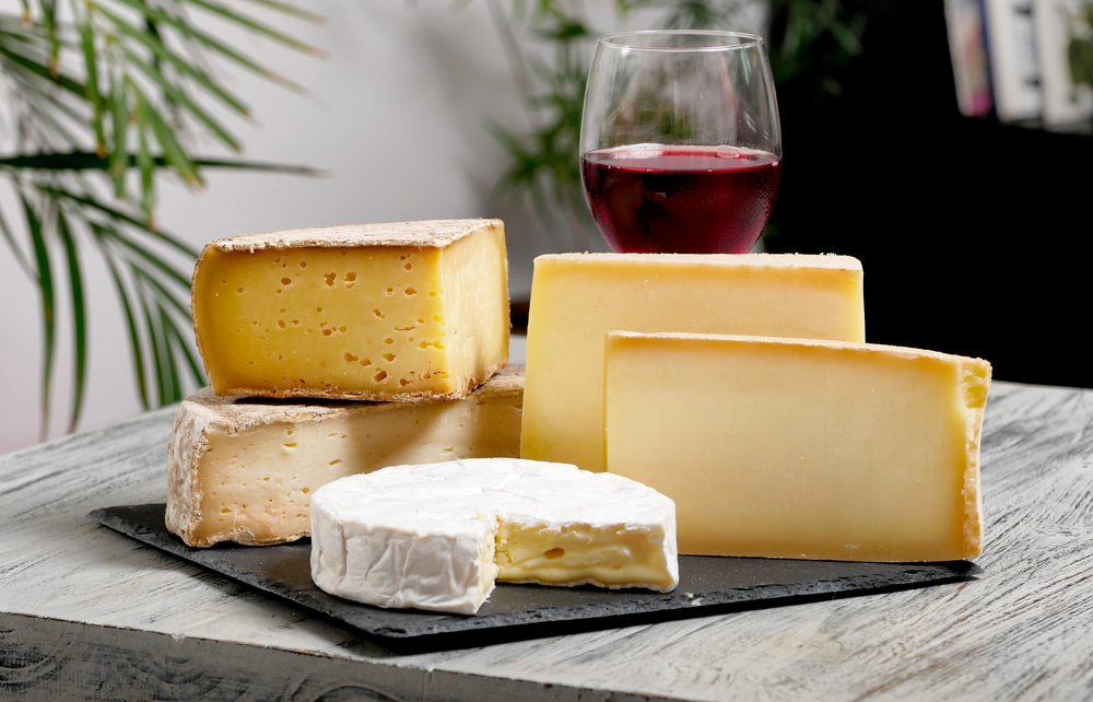 Different french cheeses with a glass of red wine