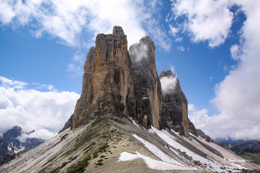 Mountain stock in Dolomites with rock towers as a summit in front of blue sky