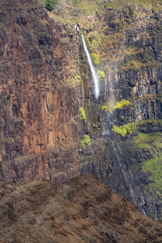 Small waterfall on vertical rock wall in Hawaii