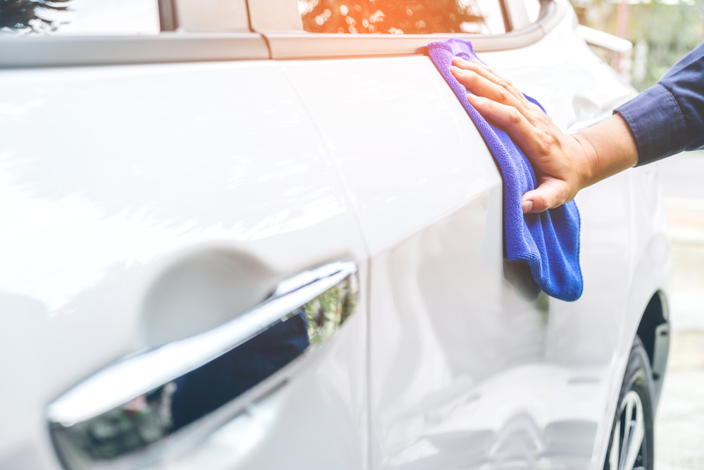man cleaning car with microfiber cloth white car
