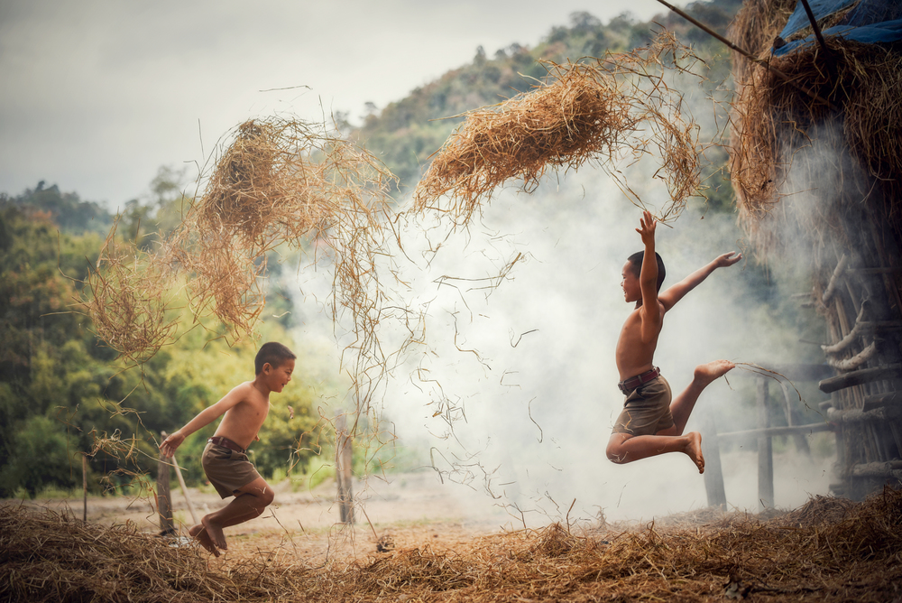 Asian boy friend children happy funny jump and playing rice straw at agricultural farm in the countryside of living life kids rural people