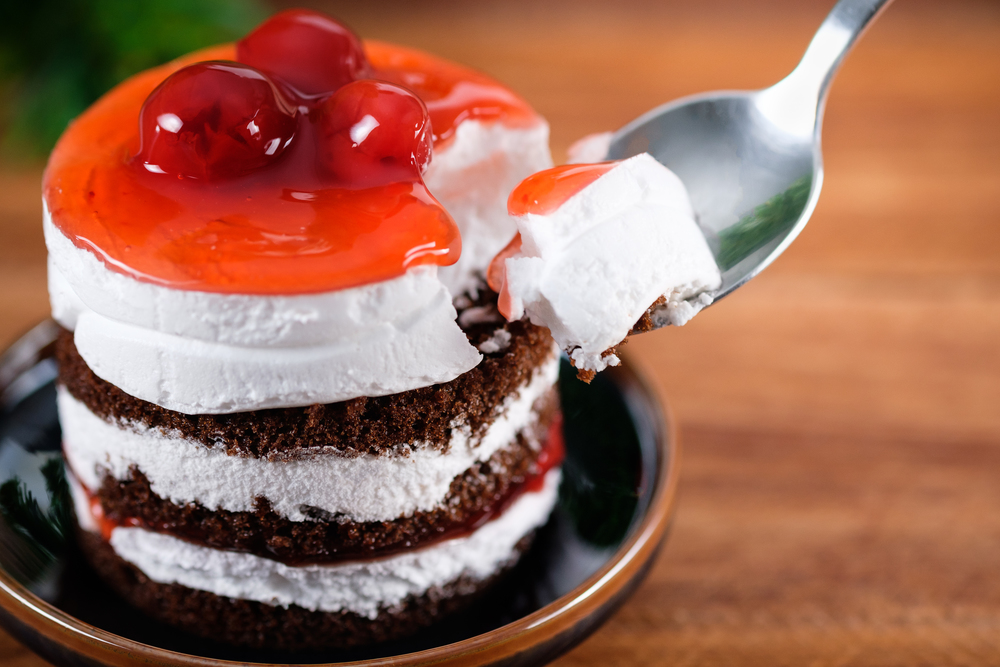 Chocolate cake with strawberry cherry and white cream on wooden table, close-up