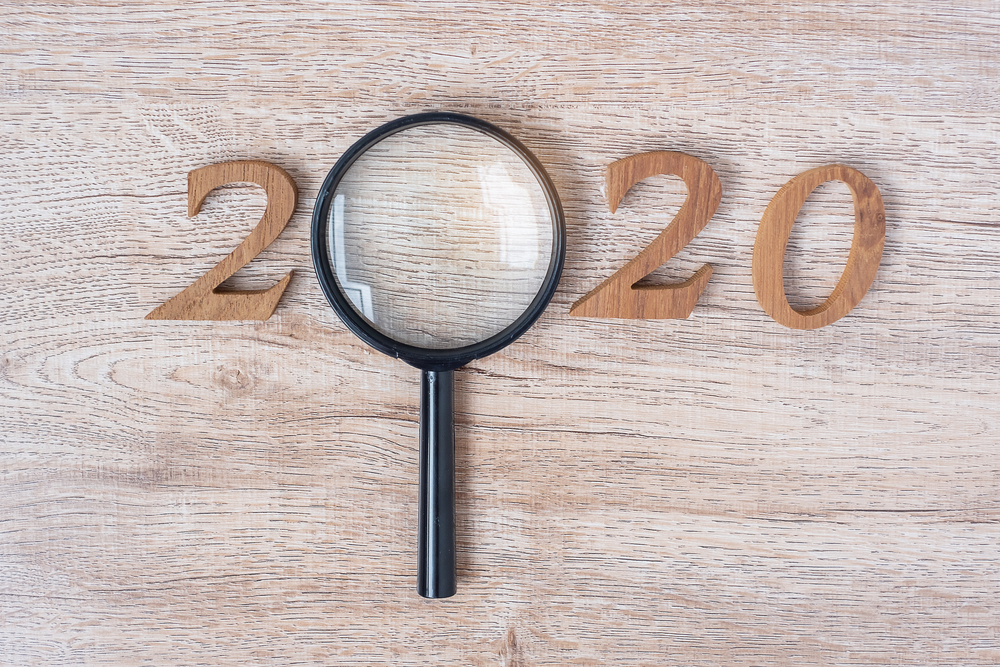 2020 Happy New year with Businessman holding glass magnifying and wooden number on table. New Start, Vision, Resolution, Strategy, Goals, Mission and Search Engine Optimization concept