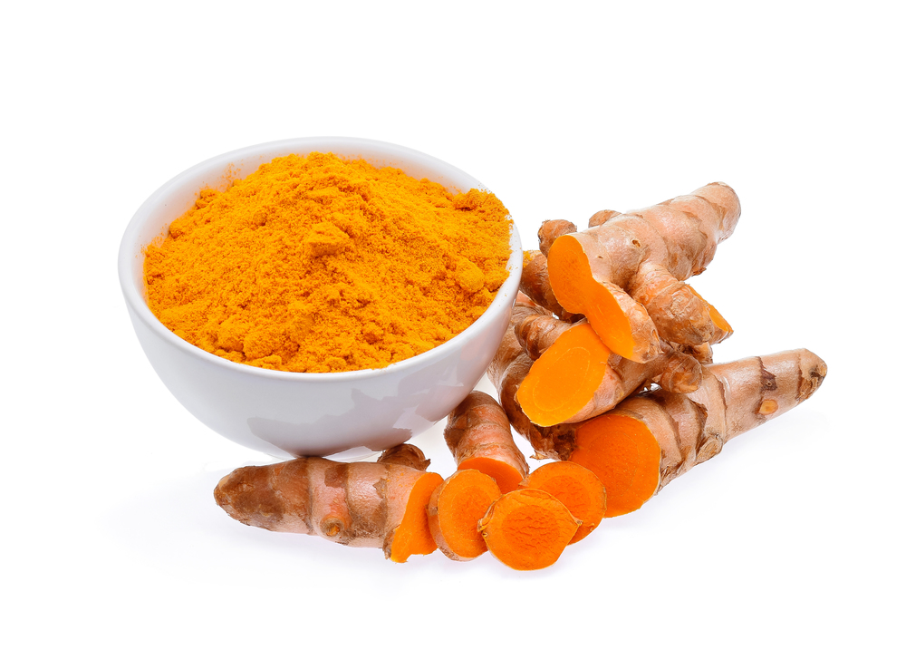 Turmeric roots and turmeric powder in white bowl isolated on white background