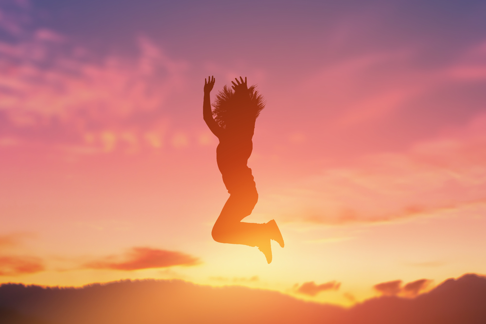 The silhouette of a happy jumping girl in a beautiful sunset