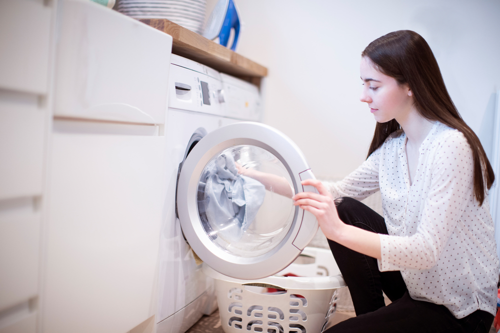Teenage Girl Helping With Domestic Chores At Home Emptying Washing Machine