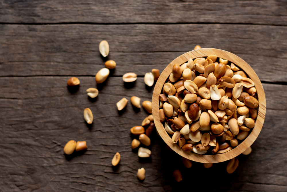 Baked peanuts put in a cup, placed on an old wooden floor.