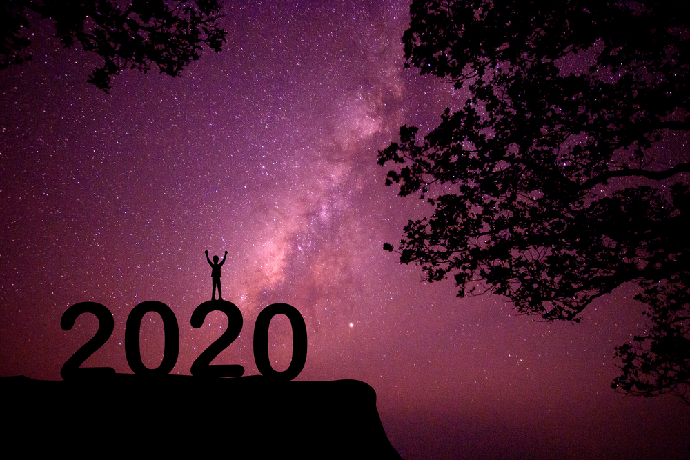 The silhouette of the child standing on the numbers happy new year 2020 with the milky way in the night sky.